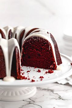 a red velvet bundt cake with white icing on a serving platter, ready to be eaten