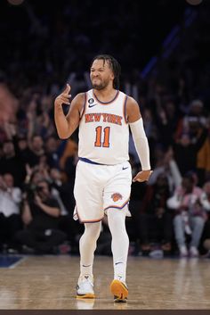 a basketball player walking on the court with his hand up in the air and smiling