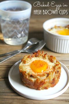 baked eggs in hash browns cups on a white plate next to a glass of water