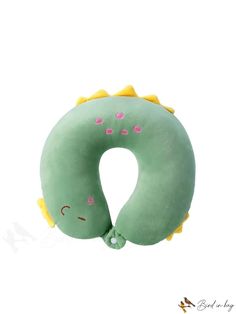 a green and yellow stuffed animal pillow with pink hearts on it's back, sitting in front of a white background