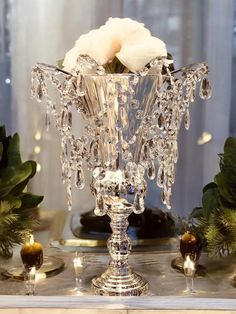 a crystal vase filled with flowers on top of a table next to candles and greenery