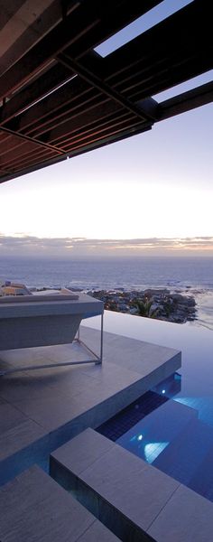 an outdoor swimming pool next to a large body of water at dusk with the ocean in the background