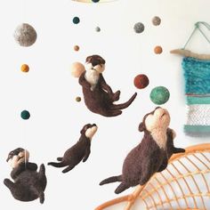 three stuffed otters hanging from the ceiling in front of a wall with space and planets on it