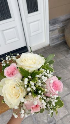 a woman holding a bouquet of white and pink flowers in her hand on the ground