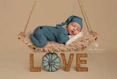 a baby is sleeping on a swing with the word love spelled out in front of it