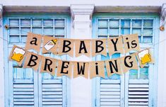 a baby's brewing banner hanging from the side of a building with blue shutters