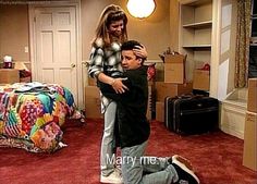 a man is being hugged by a woman in a room with red carpet and furniture