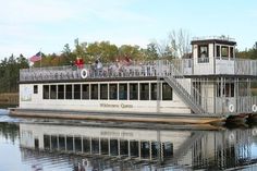 a large white boat with people on the deck and some trees in the back ground