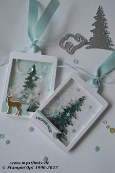 three christmas cards hanging on a string with ribbons and tags attached to them, all decorated in white and green