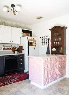 a kitchen with white cabinets, black appliances and an area rug on the floor in front of it