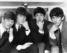 four young men in suits and ties posing for the camera with their hands on their chins