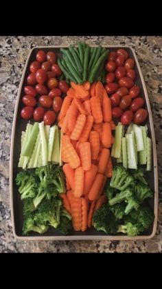 a tray filled with carrots, broccoli and tomatoes