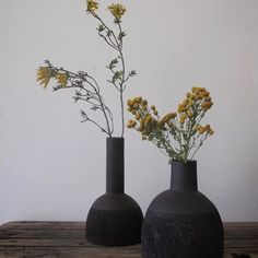 two black vases with yellow flowers in them