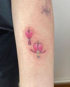 a small pink flower tattoo on the arm