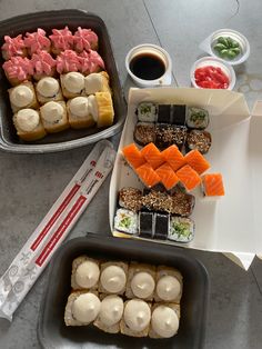 two trays filled with different types of sushi on top of a marble table