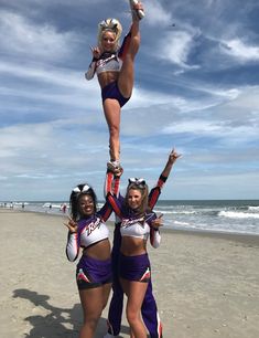 three cheerleaders are doing tricks on the beach