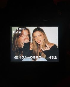 two young women are posing for the camera in front of a television screen that says topi raw