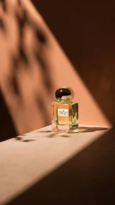 a small bottle of perfume sitting on top of a wooden table next to a wall