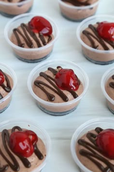 chocolate desserts with cherries and drizzled on top are arranged in small plastic dishes