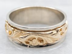 a close up of a wedding ring on a white surface with gold flowers and leaves