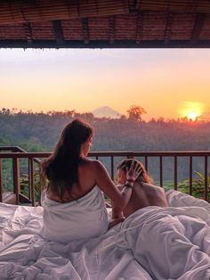 a woman sitting on top of a bed next to a man in white robes and holding a cell phone