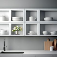 a kitchen with white cabinets and dishes on the shelves