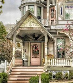 a victorian style house with pink flowers on the front door and steps leading up to it