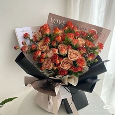 a bouquet of roses is wrapped in black ribbon and sits on a table next to a magazine