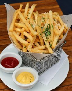 french fries with mustard and ketchup on a plate next to dipping sauces