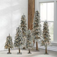 small christmas trees are lined up in front of a window