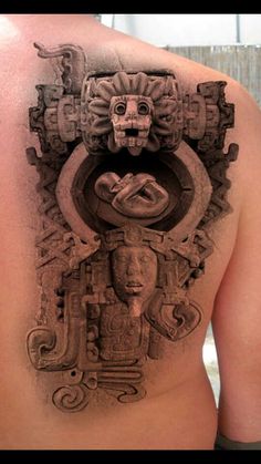 a man's back with an intricate tattoo design on his shoulder and chest area