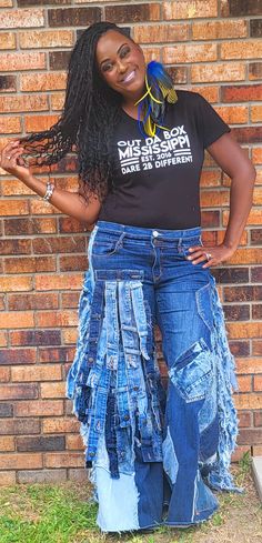 a woman standing in front of a brick wall with her hands on her hips and smiling