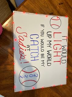 a sign that is on top of a wooden table with lights around it and an image of a baseball