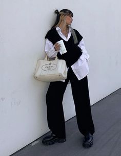 Embrace fall with this effortlessly chic ensemble. Layer an oversized white shirt with a stylish black vest sweater for a cozy yet sophisticated look. Complete the outfit with classic black pants, sleek black boots, and a pristine white Prada bag for a touch of luxury. Elevate your autumn style with this perfectly balanced and on-trend outfit.#fashion#style#trendy#falloutfit Sweater Vest Outfit, Mode Turban, Elegante Casual, Looks Street Style, Vest Outfits, Aesthetic Outfit, Outfit Style, Fashion Sale