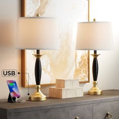 two lamps sitting on top of a dresser next to a phone