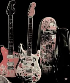 three guitars are lined up next to each other with stickers on them and one has a guitar case