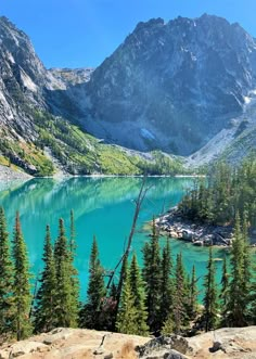 a mountain lake surrounded by pine trees in the middle of a mountainous area with blue water