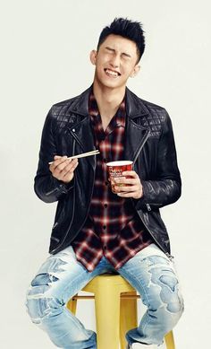 a young man sitting on top of a stool holding a cup and eating an ice cream