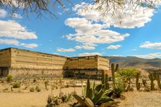 an old building surrounded by cactus and mountains