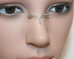 a woman's face with two nose piercings on her forehead and one eye open