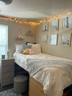 a bed room with a neatly made bed and lots of pictures on the wall above it