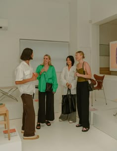 four women standing in a room talking to each other