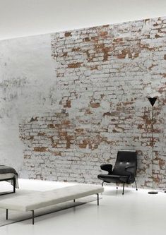 a living room with brick wall and black chair next to the couch in front of it