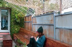 a woman sitting on a wooden bench next to a building