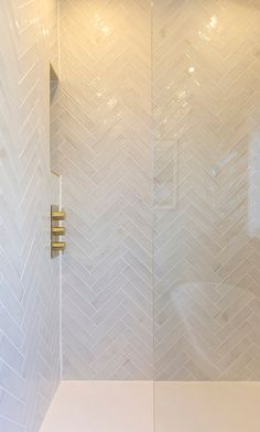 a shower with white tile and gold fixtures