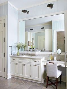 a white bathroom with two sinks and a large mirror above the sink, along with a chair