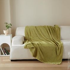 a white couch with a green blanket on it