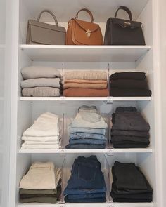 a white closet filled with lots of different types of clothes and handbags on top of shelves