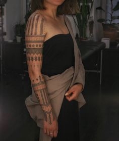 a woman with a tattoo on her arm is standing in a room and looking at the camera