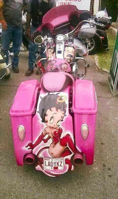 a pink motorcycle parked on the side of a road next to other motorcycles and people